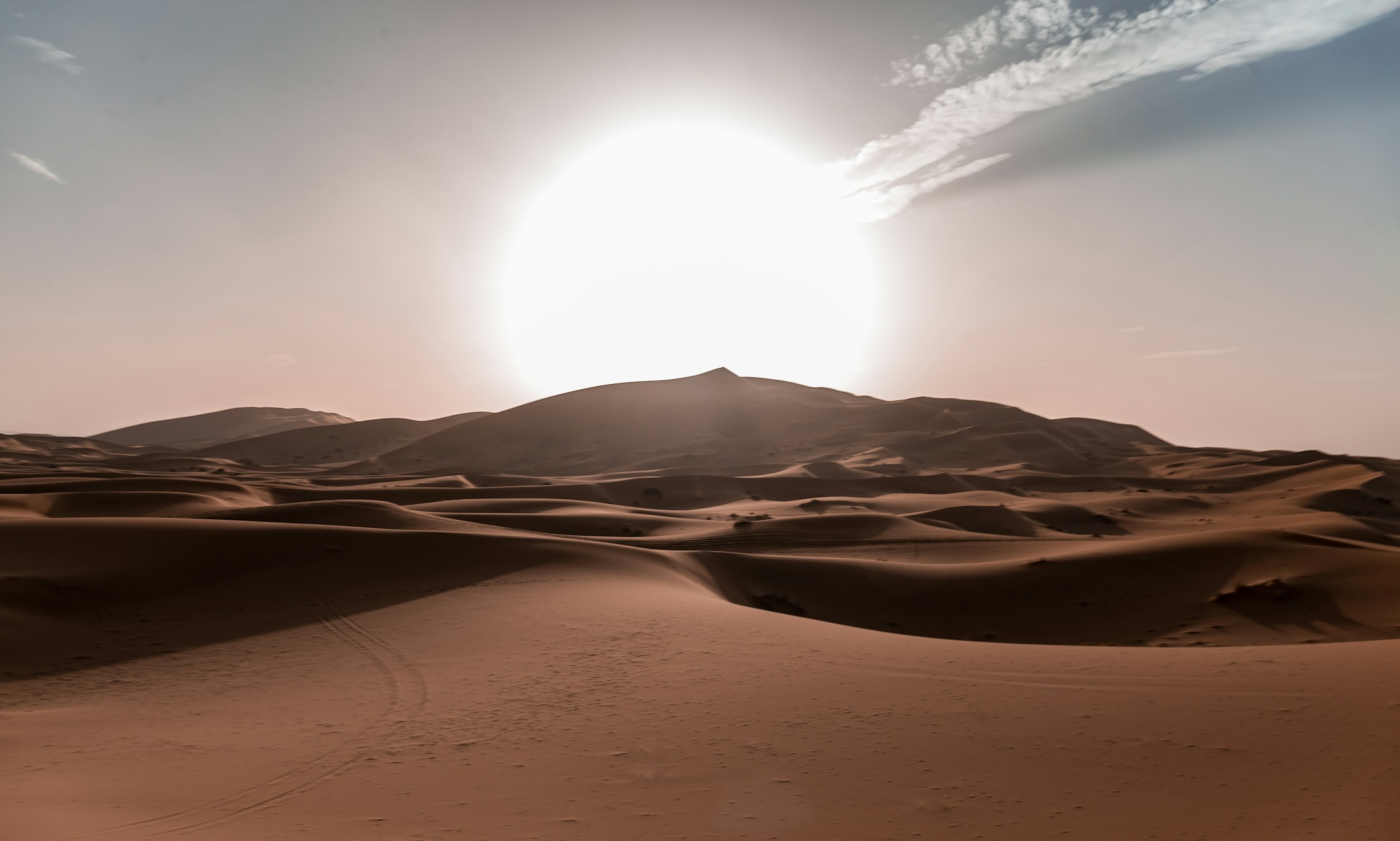 The setting sun above rolling Sahara sand dunes in Morocco